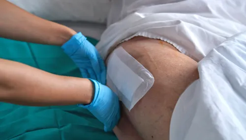 Krankenschwester, die Pflaster auf das Bein eines Patienten aufträgt