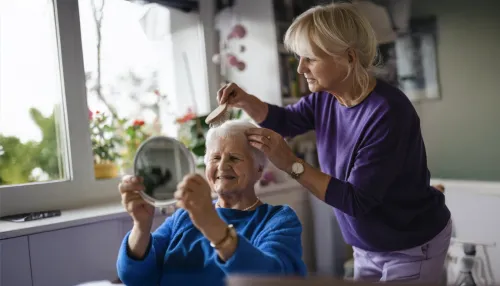 Frau kämmt Haare ihrer alten Mutter