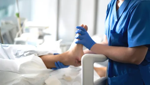 Krankenschwester untersucht die Fußwunde des Patienten im Krankenhausbett