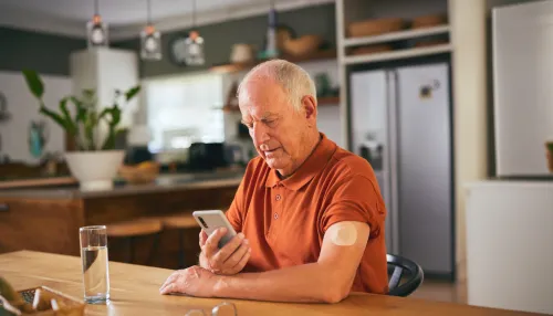 Diabetischer Senior, der Glukose in der digitalen App überprüft