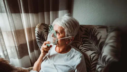 Seniorin trägt Sauerstoffmaske Sitzt Mit Hund Auf Stuhl Zu Hause